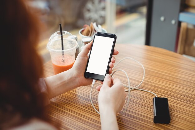 Businesswoman using portable power bank to charge her phone