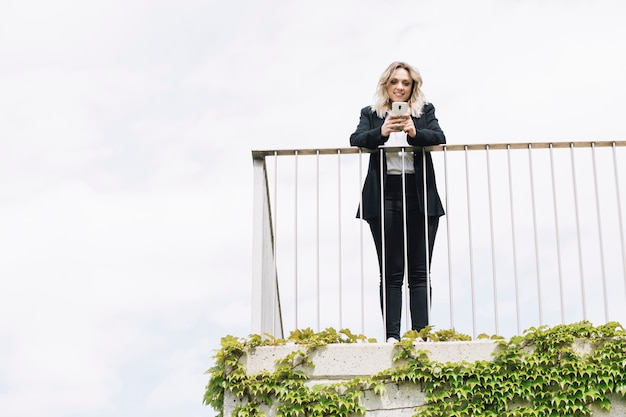 Foto gratuita donna di affari che per mezzo dello smartphone sul balcone