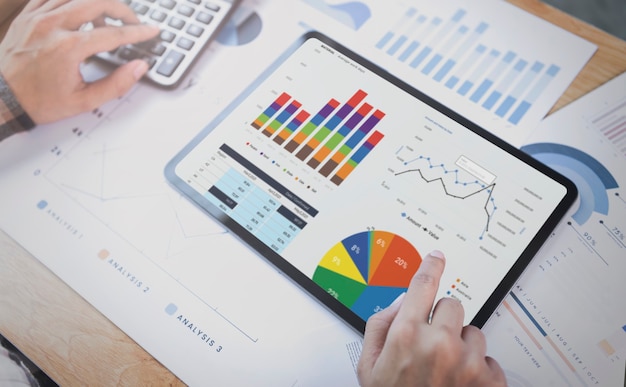 タブレットを使用してグラフ会社の財務戦略統計の成功の概念とオフィスルームでの将来の計画を分析する実業家。