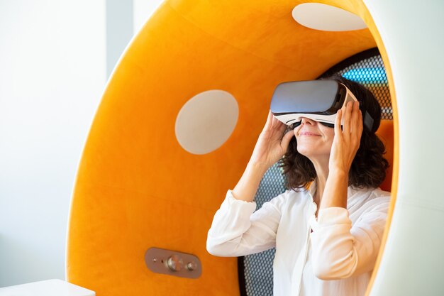 Businesswoman in VR headset sitting in spherical chair