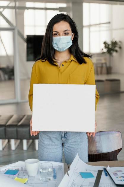 Businesswoman wearing a medical mask while holding a blank card