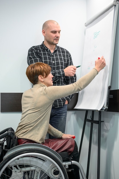 Free photo businesswoman in wheelchair writing on a flip chart