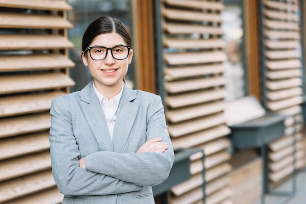 Businesswoman with arms crossed in front of house