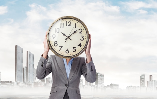 Free photo businesswoman with a big clock in front of her head