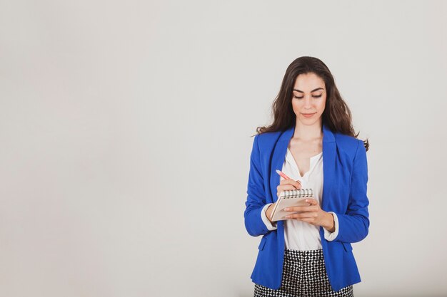 Businesswoman with blue jacket writing on her notebook