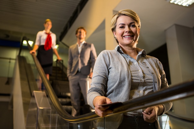 Businesswoman with boarding pass standing on escalator