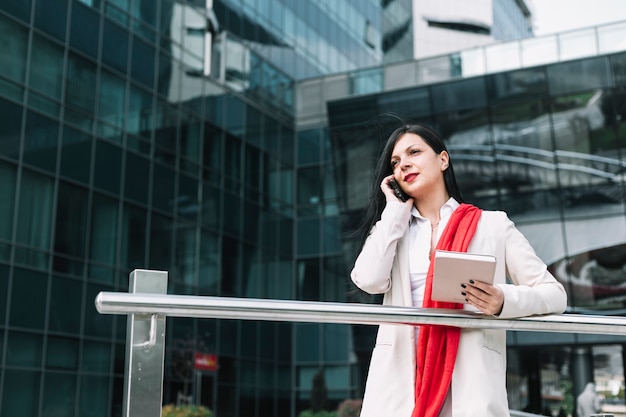 Donna di affari con il diario che parla sul cellulare