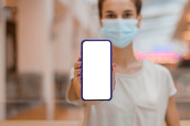 Businesswoman with face mask showing a blank phone