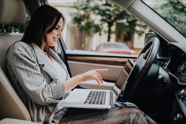 Businesswoman with a laptop in her car in the street