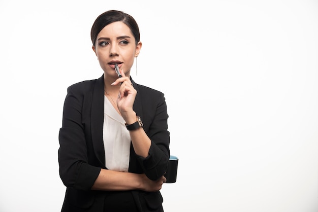 Free photo businesswoman with pencil and cup on white wall.