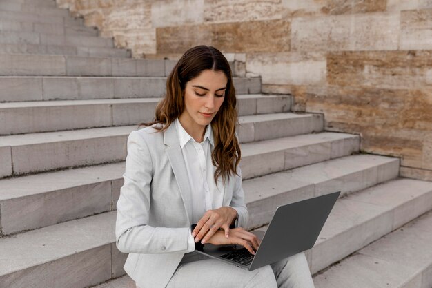 Businesswoman with smartwatch working on laptop while sitting on stairs