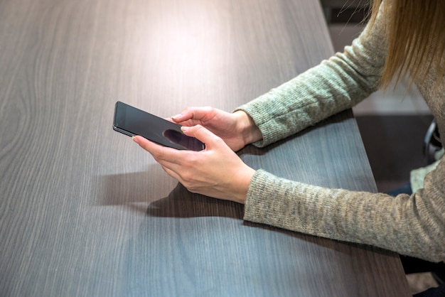 Businesswoman work in office environment. Close up view of businesswoman using her phone at her desk in office