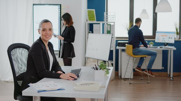 Businesswoman working on computer with data charts for management strategy in corporate office. Entrepreneur using technology and monitor for research analysis and design planning.