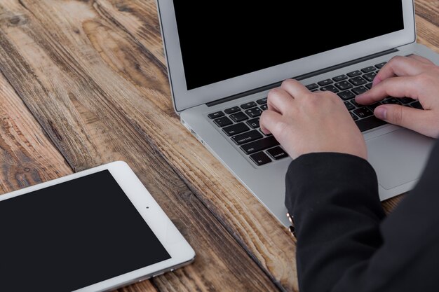 Businesswoman working with laptop next to a tablet