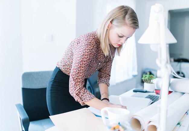 Businesswoman writing on file over desk in office