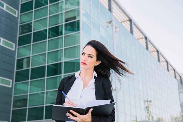 Businesswoman writing in folder