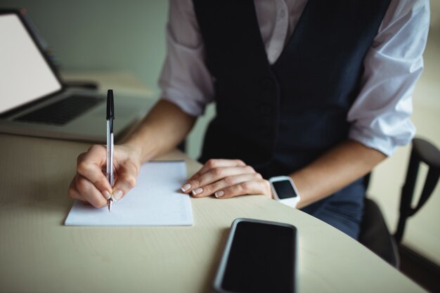 Businesswoman writing on notepad