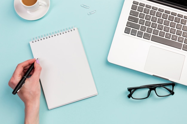 A businesswoman writing on spiral notepad on the office desk