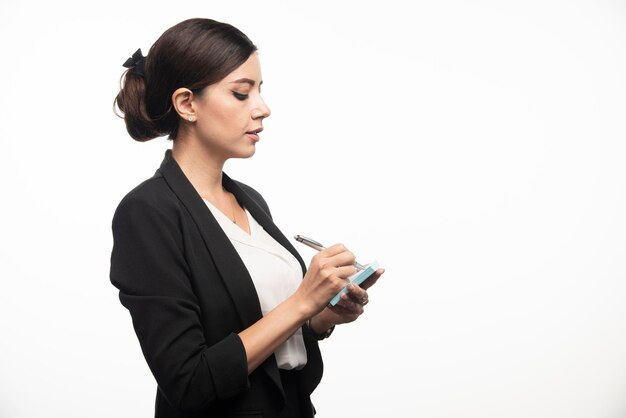 Businesswoman writing in sticker with a pencil on a white background. High quality photo