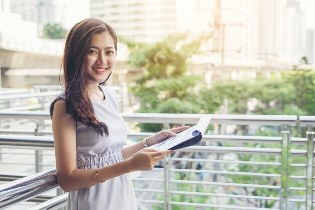 Businesswomen discussing over paperwork against railing. Business people concept.