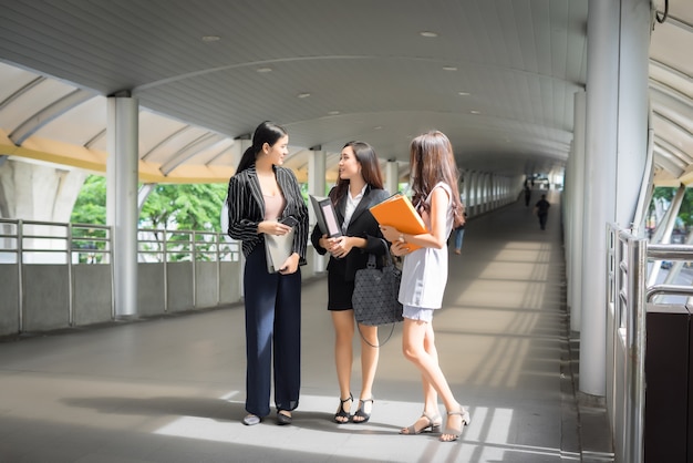 Businesswomen discussing over paperwork together against railing. Business people concept.