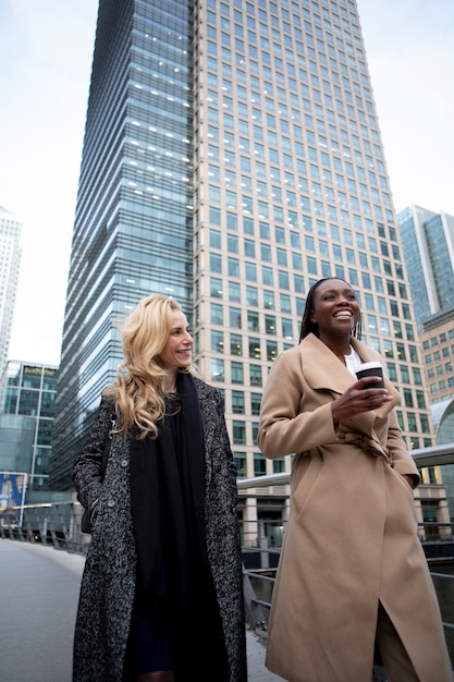 Free photo businesswomen going to work together in the city while talking and drinking coffee