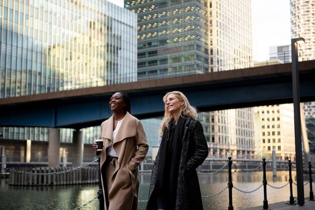 businesswomen going to work together in the city while talking and drinking coffee