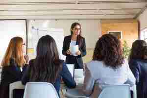 Free photo businesswomen looking at speaker with papers