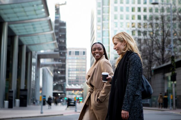 Businesswomen walking together in the city and drinking coffee