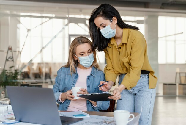 Деловые женщины в медицинских масках на работе