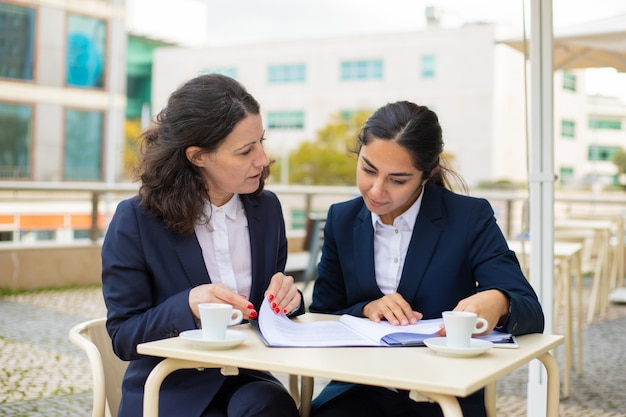 Free photo businesswomen working with papers in outdoor cafe