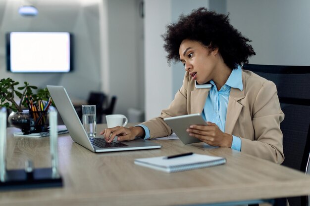 Busy African American female entrepreneur working on wireless technology in the office