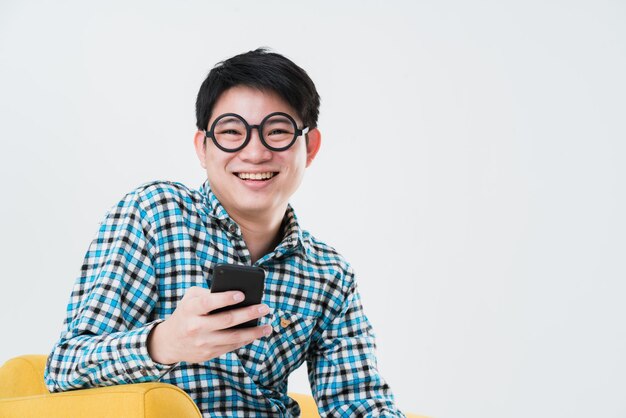 Busy asian man tshirt hand hold smartphone on sofa