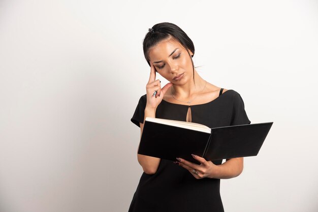 Busy businesswoman reading notes on white wall.