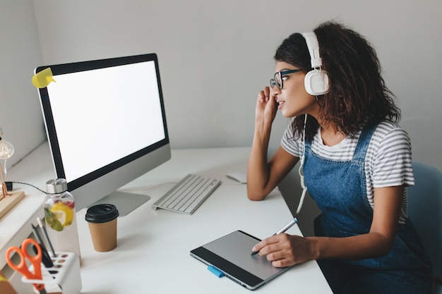 Busy cute girl in vintage outfit using tablet for work spending time in office