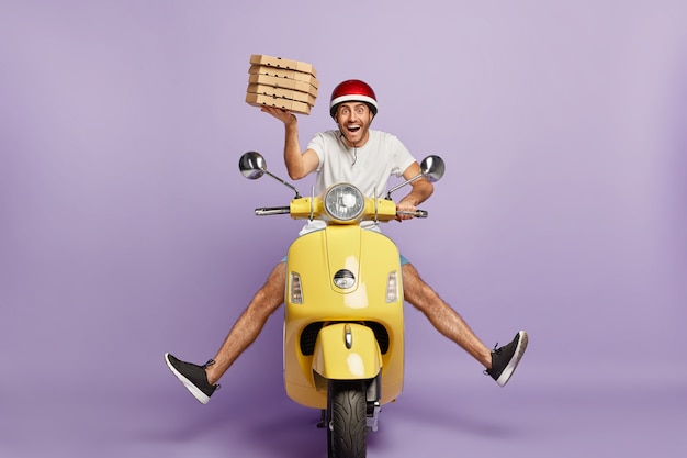 Busy deliveryman driving scooter while holding pizza boxes