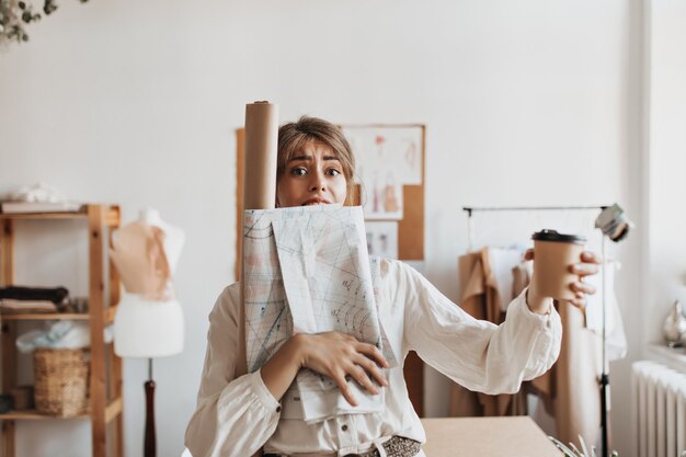 Busy designer woman holds coffee cup