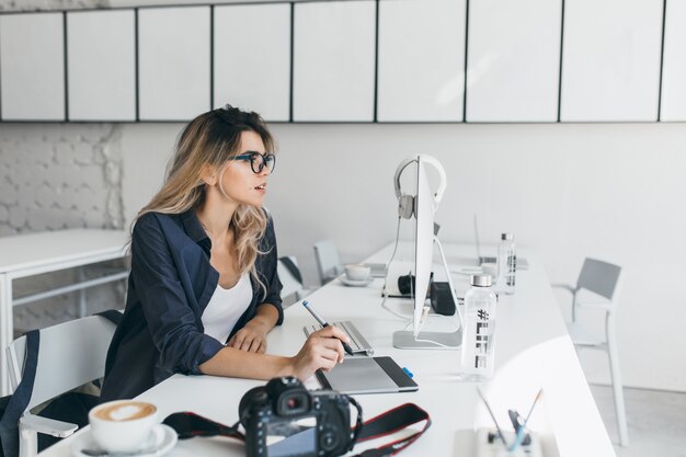 Busy female european student working with computer and drinking coffee