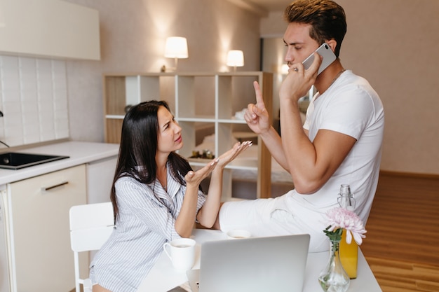 Busy guy talking on phone during lunch with wife in home