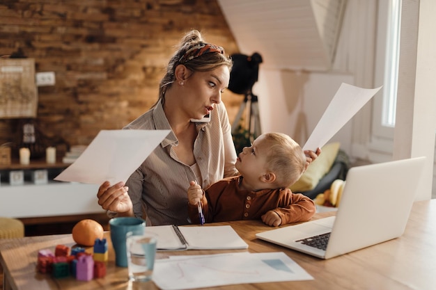 Busy single mother babysitting her small son while working at home