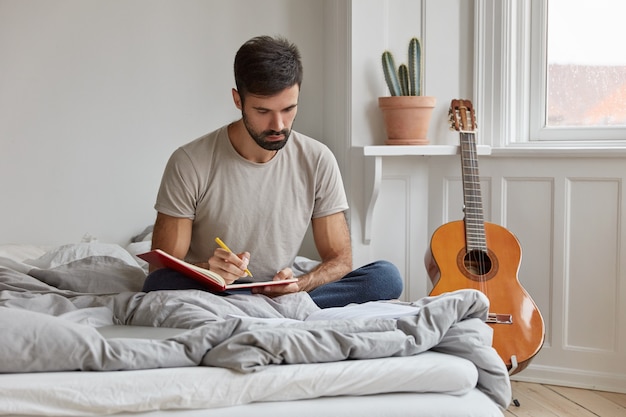 busy talented musician writes words of new song into notebook