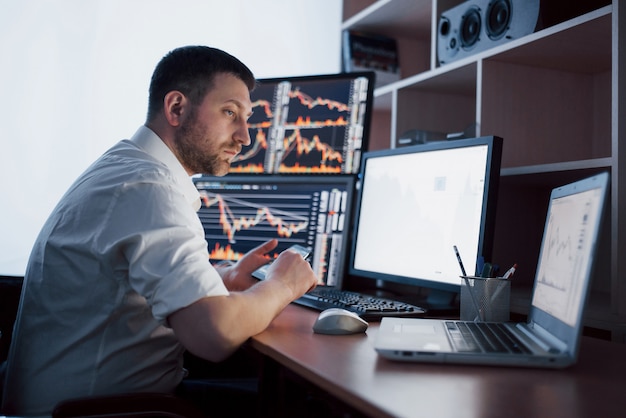 Busy working day. Close-up of young businessman looking at monitor while sitting at the desk in creative office