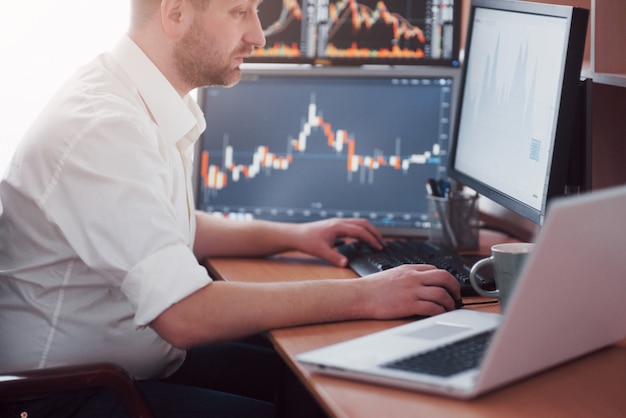 Busy working day. Close-up of young businessman looking at monitor while sitting at the desk in creative office