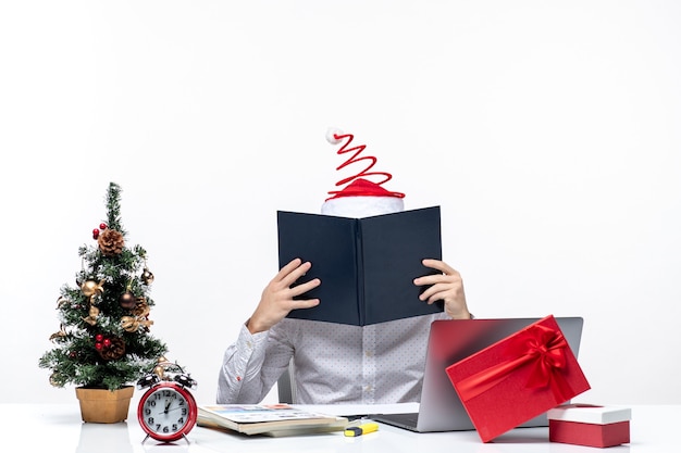 Free photo busy young businessman with funny santa claus hat checking information in documents in the office on white background