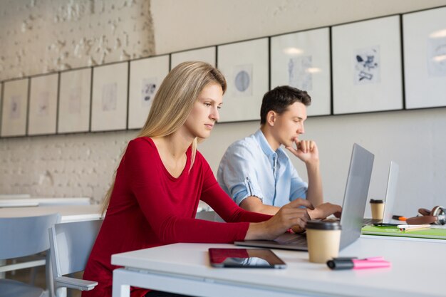 Busy young man and woman working on laptop in open space co-working office room