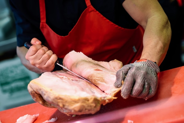 Macellaio che disossava un prosciutto in una moderna macelleria