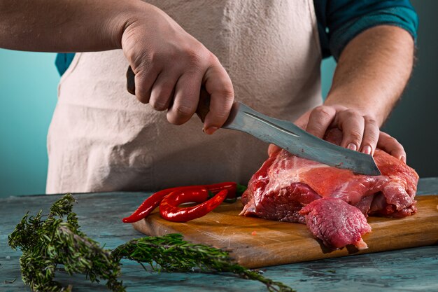 Butcher cutting pork meat on kitchen