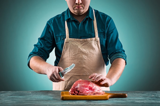 Butcher cutting pork meat on kitchen