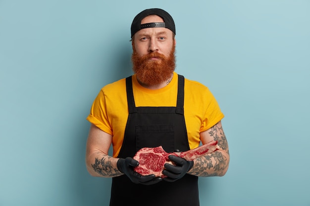 Free photo butcher man with ginger beard holding meat