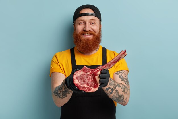 Butcher man with ginger beard holding meat